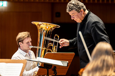 ein Teil des Orchester, Dirigent und Wettbewerbskandidat spielen live auf einer Konzertbühne