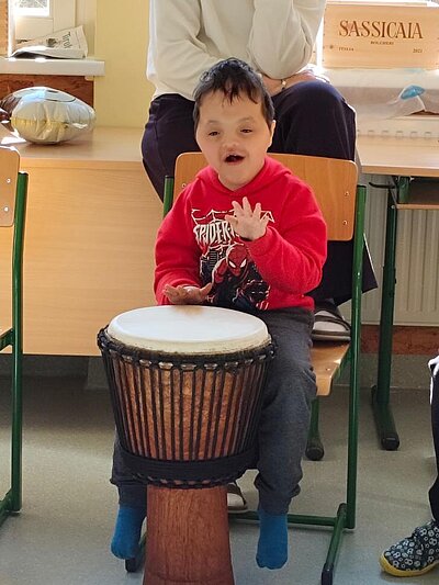 Ein lächelnder Schüler trommelt auf einer Djembe