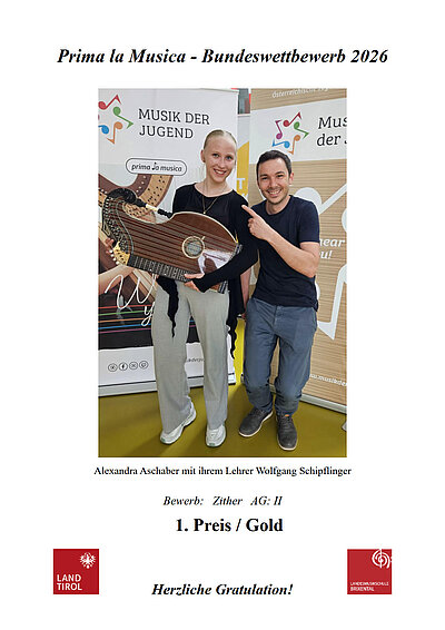 Eine strahlende Alexandra Aschaber und ihr Lehrer Wolfgang Schipflinger mit Zither vor den Plakaten vom Prima la Musica Bundeswettbewerb 2026