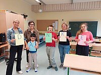 Eine Gruppe von Lehrerinnen und Schülern der Allgemeinen Sonderschule Hopfgarten halten bunte A4-Blätter mit den Buchstaben DANKE - also Danke in die Kamera
