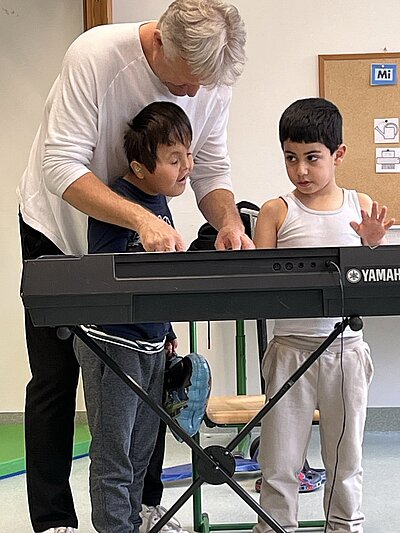 Der Lehrer mit 2 begeisterten Schülern am Keyboard