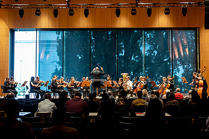 Orchester, Dirigent und Wettbewerbskandidat spielen live auf einer Konzertbühne