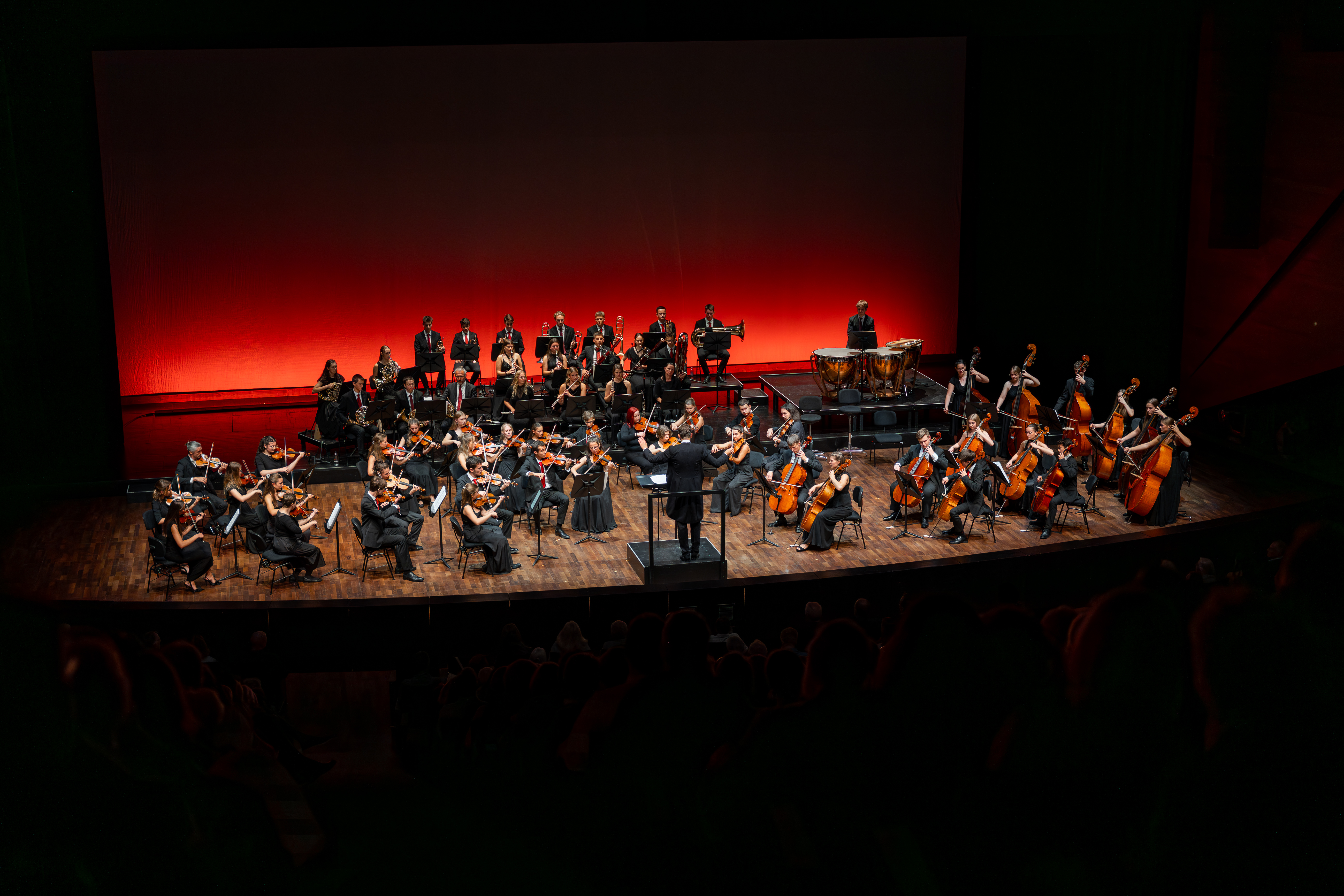 Orchester auf einer modernen Konzertbühne im roten Scheinwerferlicht